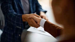 Close up of coworkers handshaking while greeting during business meeting in the office